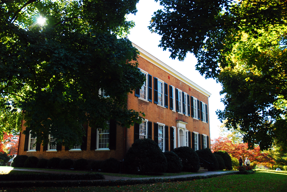 The brick My Old Kentucky Home as seen through green trees.