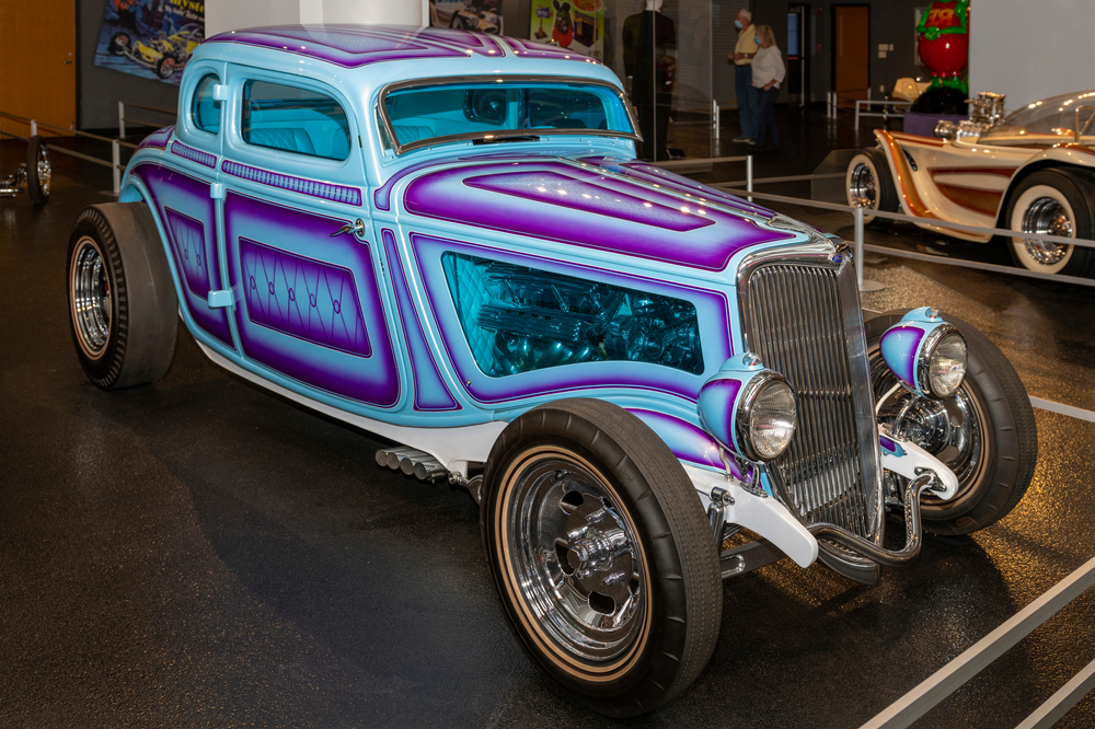 An old Corvette painted blue and purple in a museum.