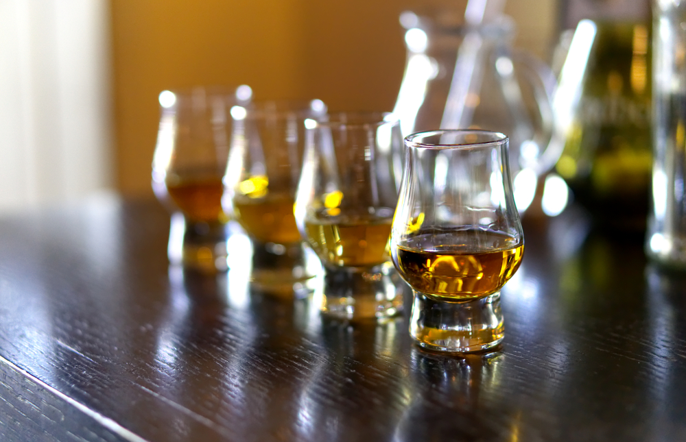 A flight of whiskey (four glasses on a bar) is one of the many offerings at Brandy Bar, one of the best things to do for adults in Hendersonville NC. 