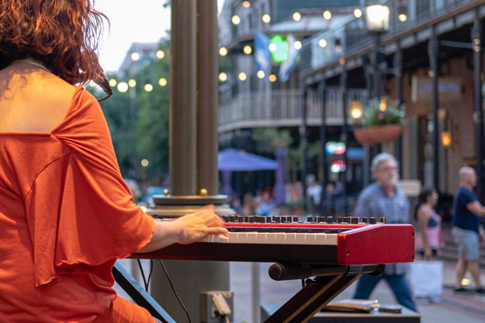 A women playing the piano in the Warehouse District of NOLA. It is one of the best places to stay in New Orleans