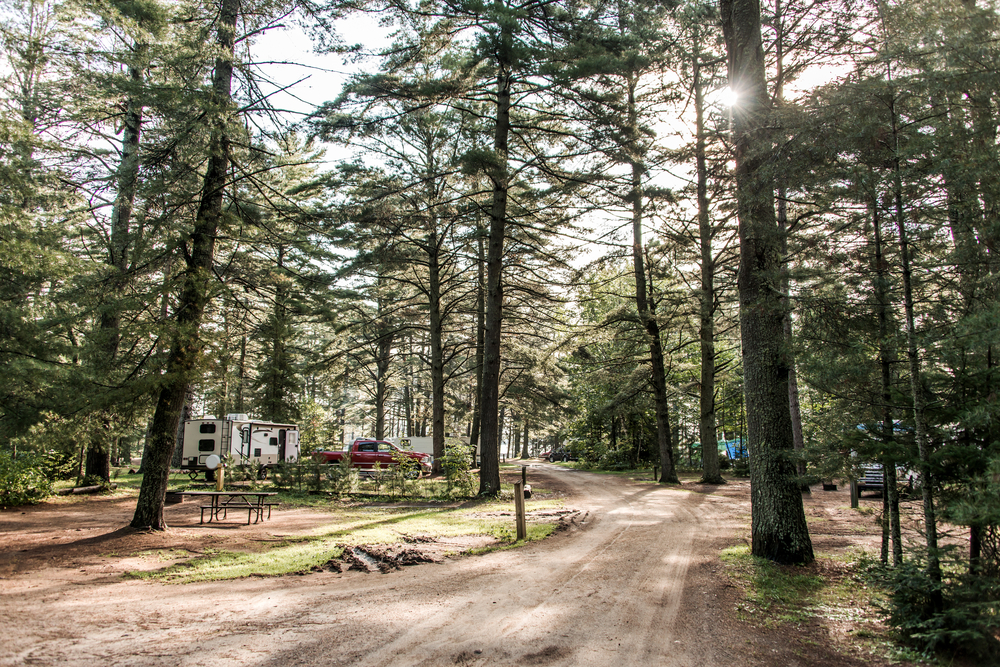 photo of a trail with a red truck and RV off to the left with a picnic table 