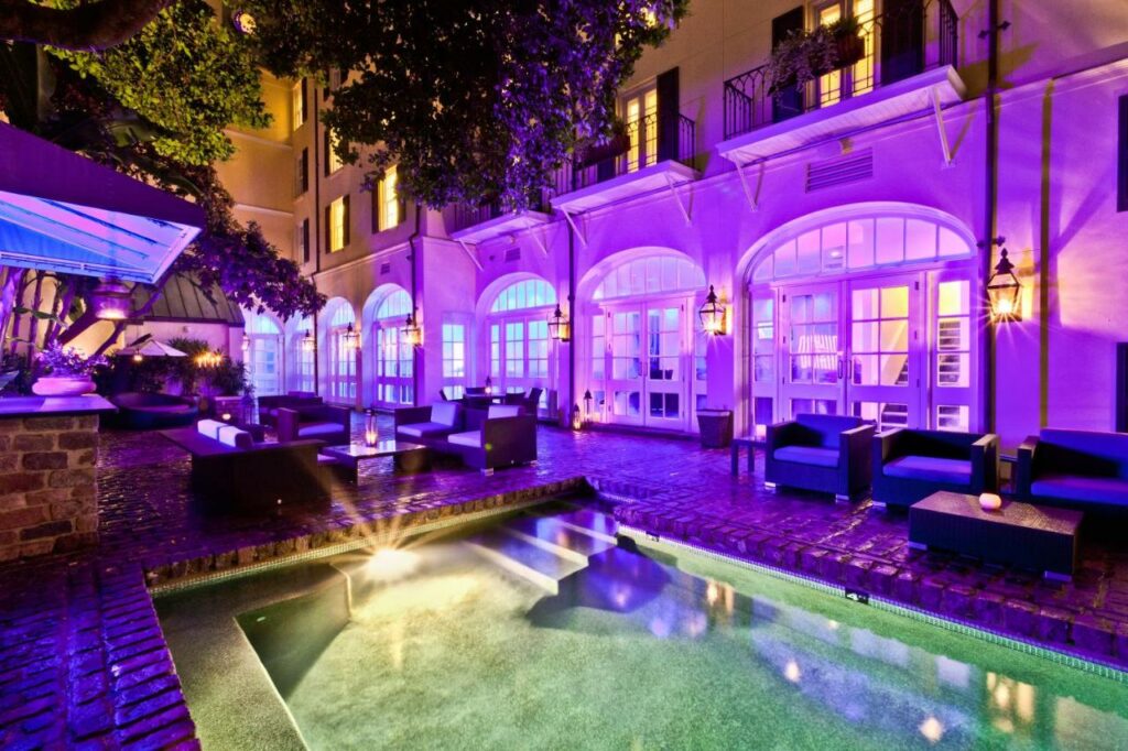 a photo of the white exterior of Hotel Le Marais at Night, illuminated with bright purple light that gives the illusion of the hotel being purple