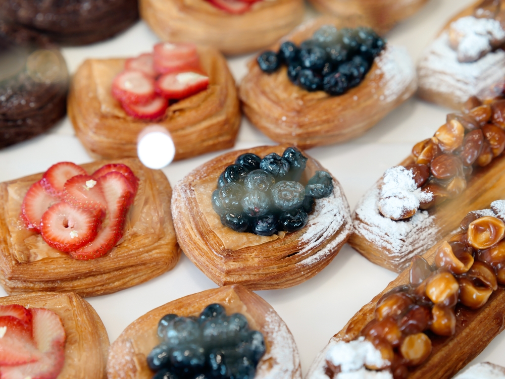 rows of danishs and bakery items with toppings on them