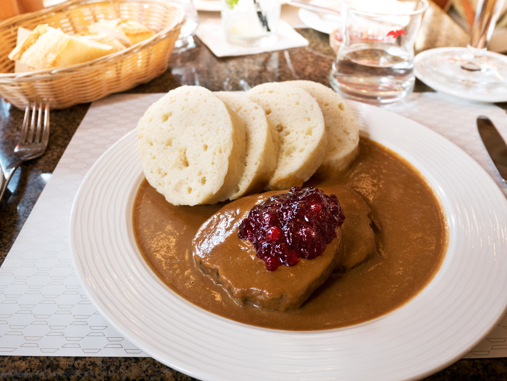 a plate of Czech food on the table. Meat and sauce on plate with four slices of bread. 