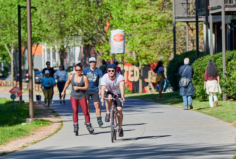 Atlanta Beltline showing people biking walking and skating on the paved area. 