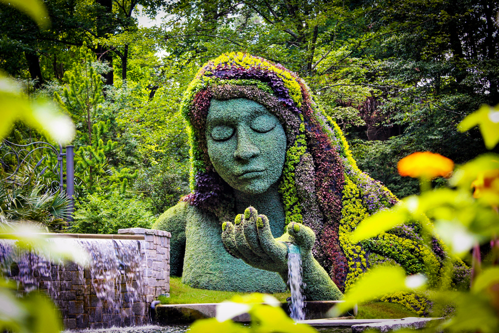 Earth goddess plant sculpture in the Atlanta Botanical gardens for the, Once Upon a Time theme. A sculpture of a women covered in plants with a waterfall in her hand. 