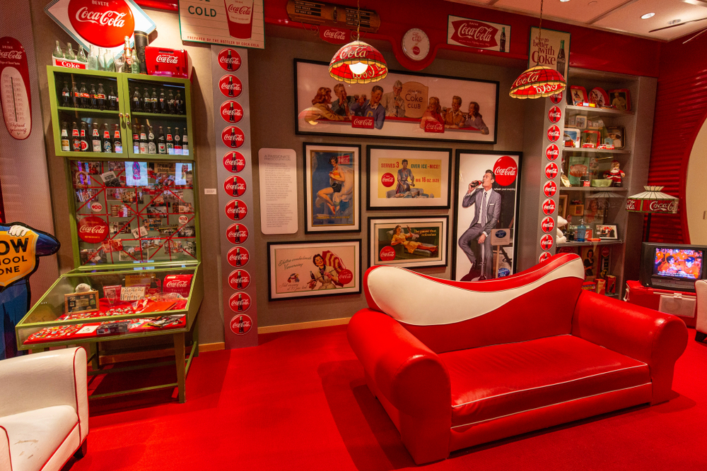 inside the Coca Cola Museum with a red soaf, red carpet and coke memorabilia on the wall. 