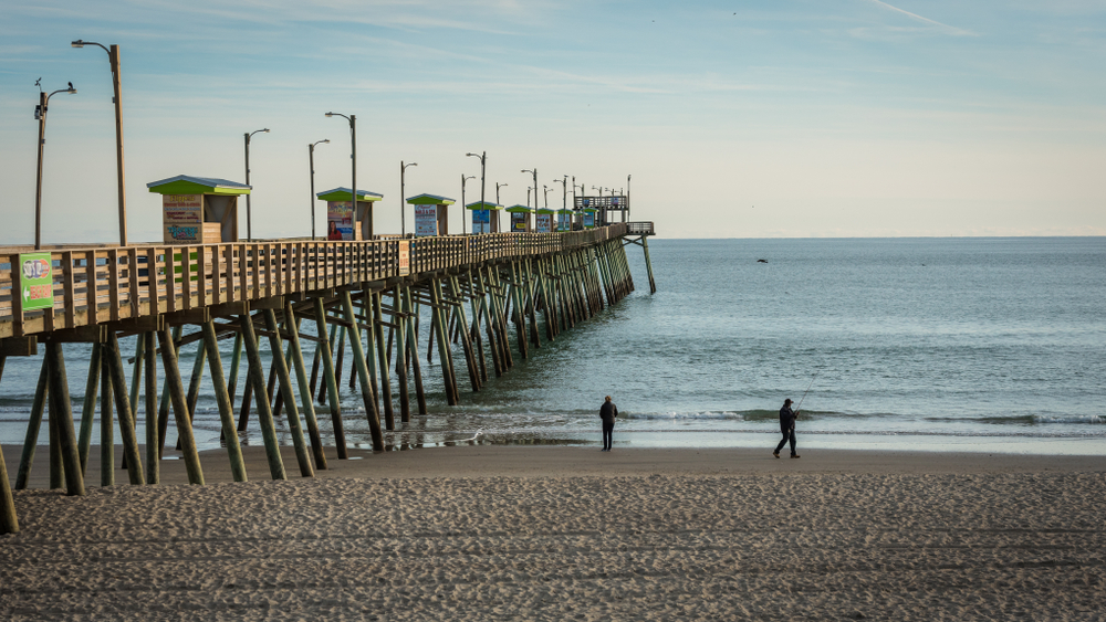 people fishing on beach near pier