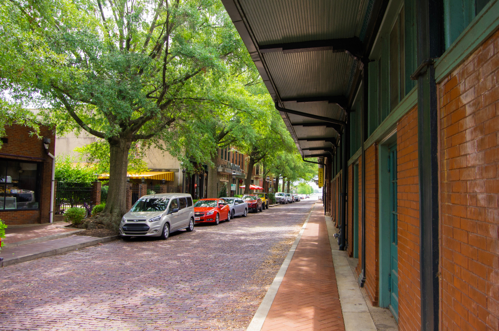 brick building on streets edge, cars parked along road