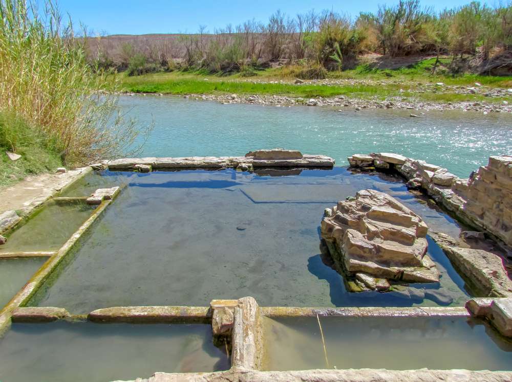 The natural hot spring at Big Bend National Park on the edge of a river on a sunny day, one of the best hidden gems in Texas. 