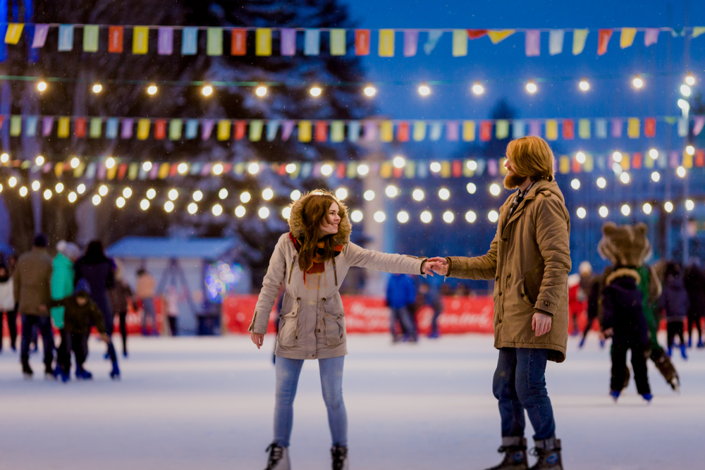 outside iceskating with hanging lights and a couple holding hands
