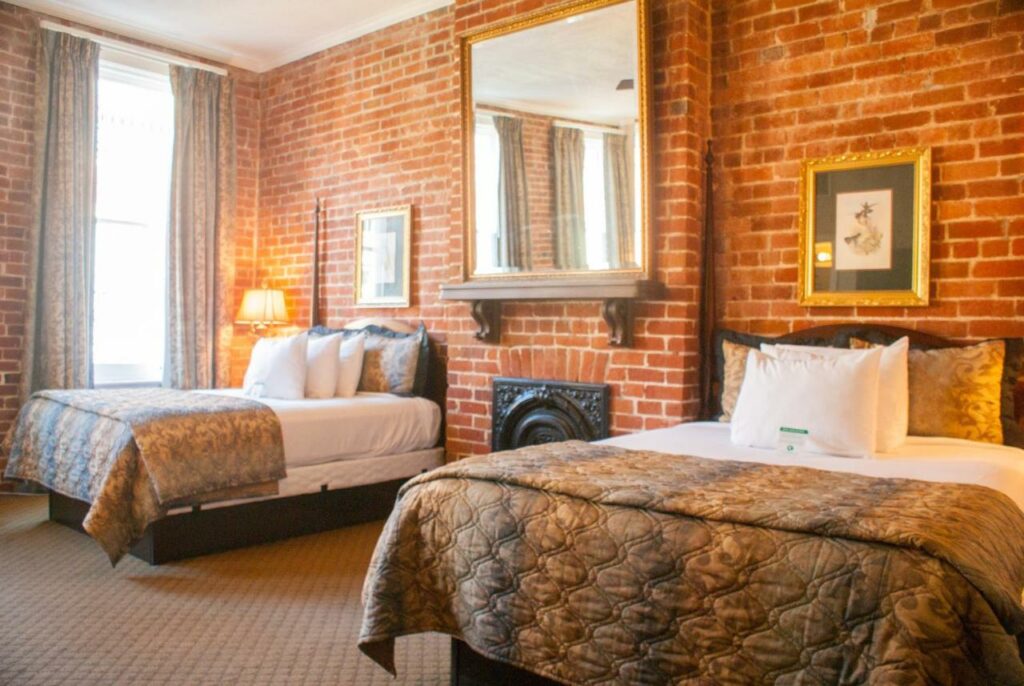 an exposed brick wall with a large mirror and classic furnishings featured in Place D'Armes