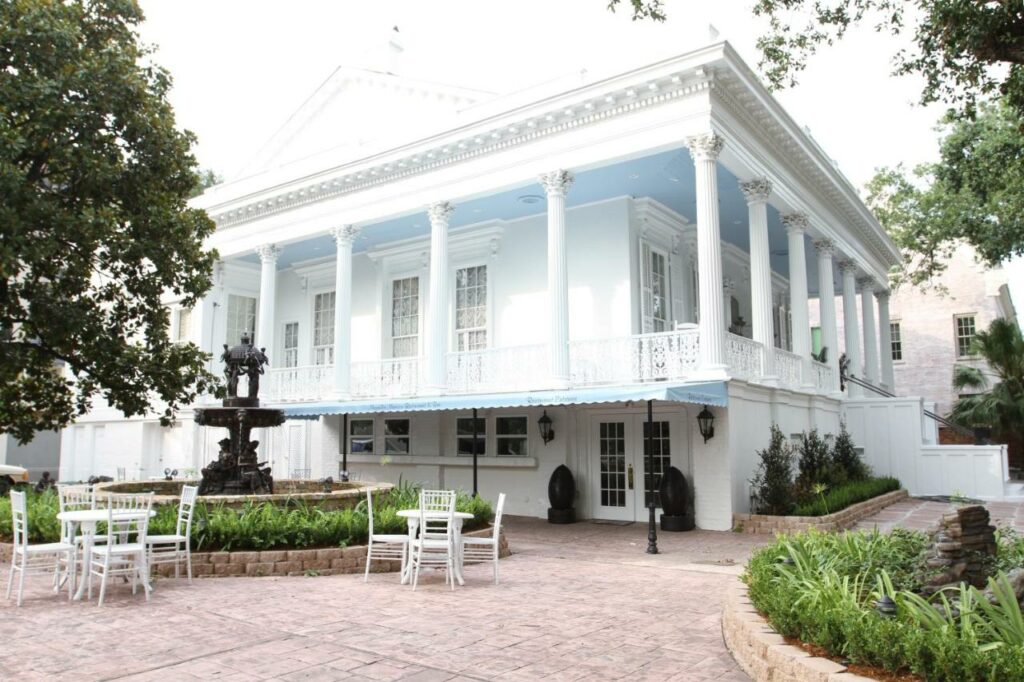 white colonial-louisiana house with great white iron details and classic landscaping attending one of the haunted hotels in New Orleans 