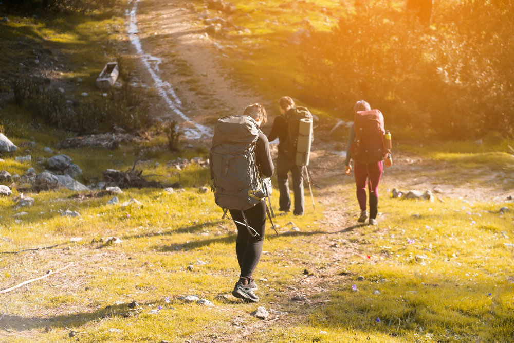 Friends hiking together in the mountains at sunset 