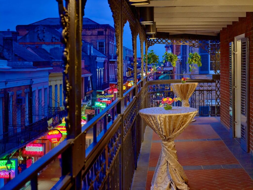 photo of an iron-wrapped balcony with two tables wrapped in gold table cloth at one of the best hotels in New Orleans 