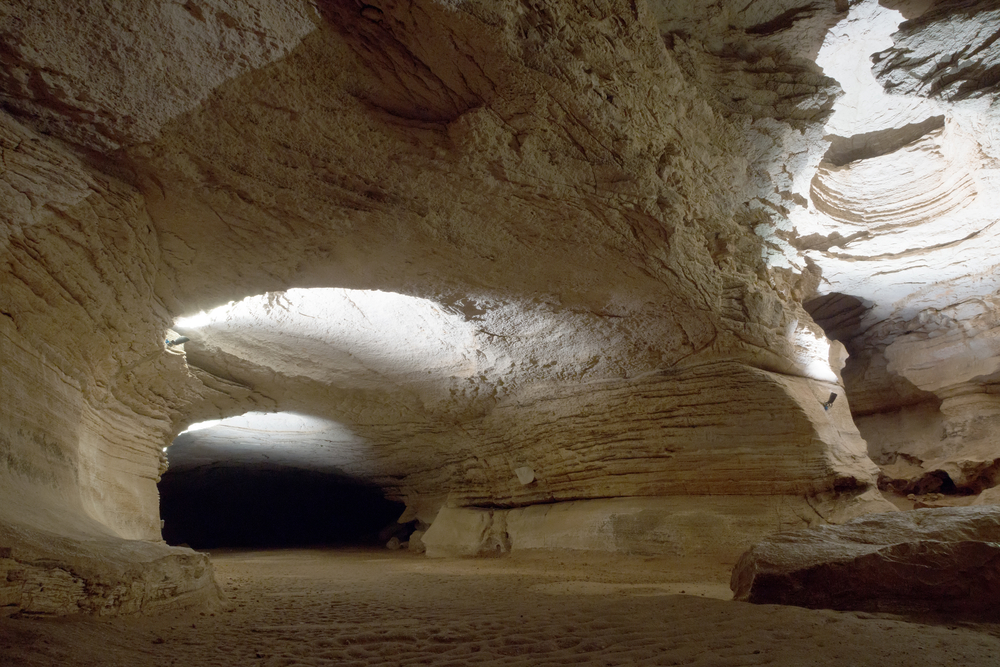 The inside of a massive cavern made of a light colored stone, one of the best hidden gems in Texas