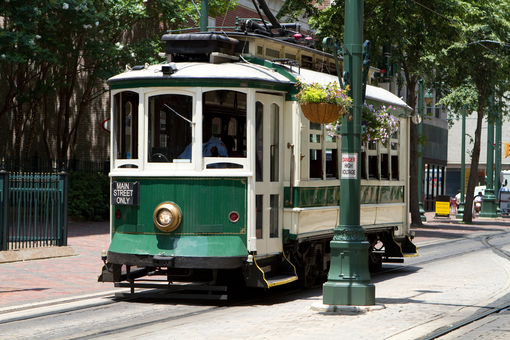 A green and white trolley on the main street that you can use during a weekend in Memphis.