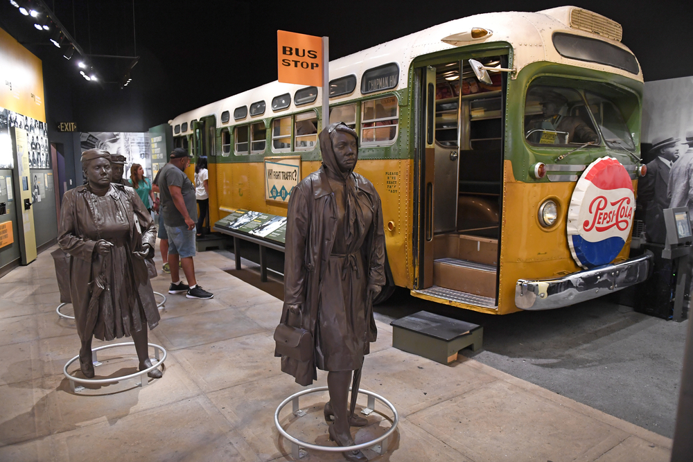 A display about busing during the Civil Rights Movement at the National Civil Rights Museum. There is a bus from the 1960s and then bronze statues depicting people near the bus. 