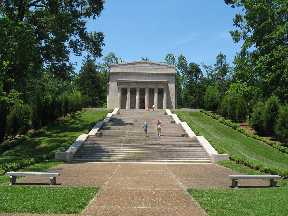 large staircase leading to old stone building with grass and trees on both sides