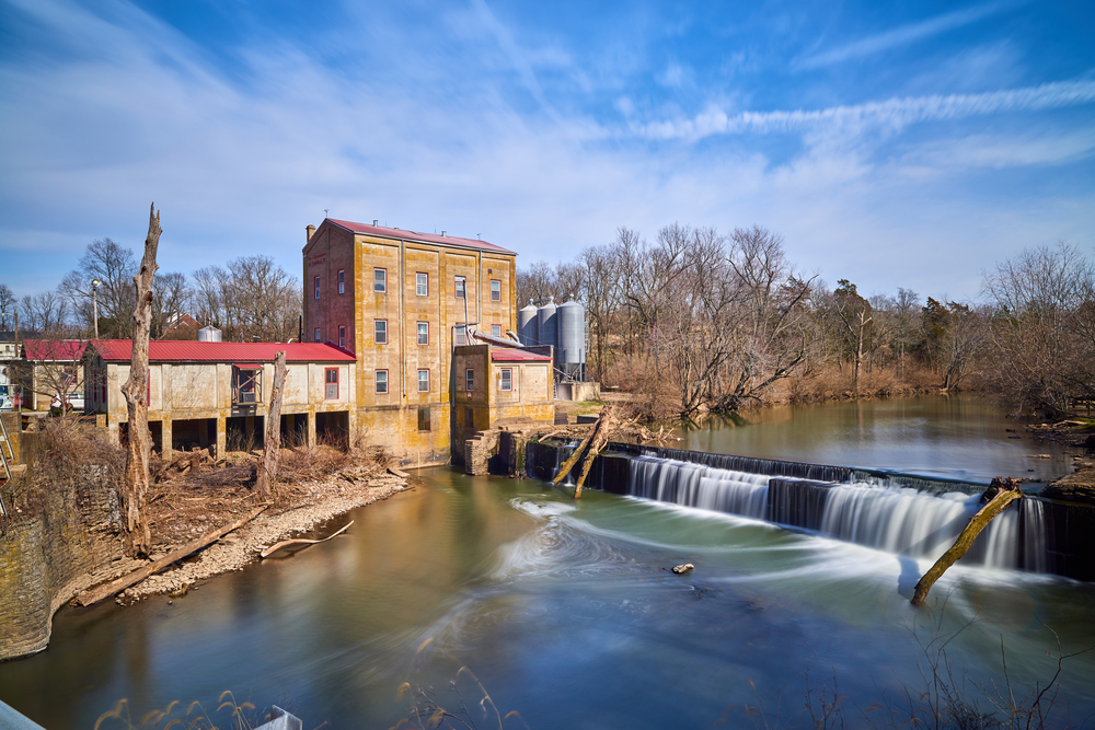 waterfall with building in background surrounded by trees