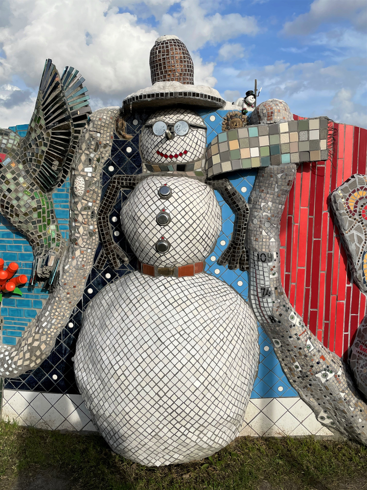 A large mosaic of a snowman with other mosaics next to it at a park