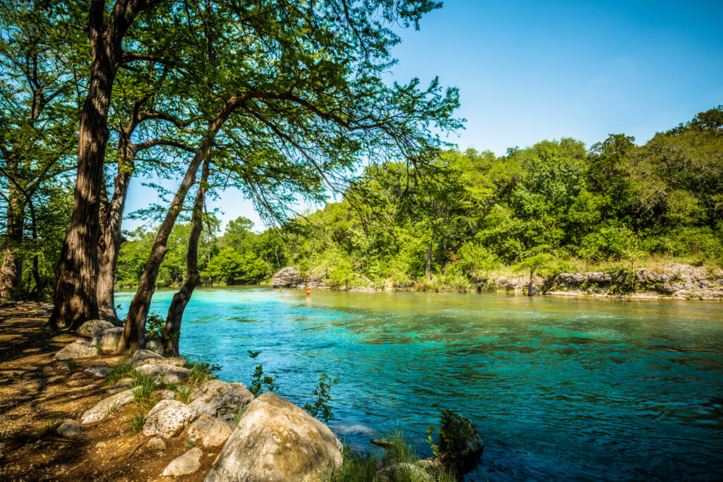 Guadalupe River New Braunfels showing the river and the banks with foilage. One of the best weekend getaways in Texas