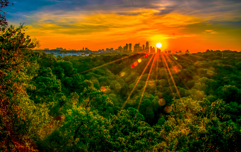 Austin Texas nature trail hiking at sunrise with golden hour sunburst glowing over the city skyline cityscape. The article is about weekend getaways in Texas. 