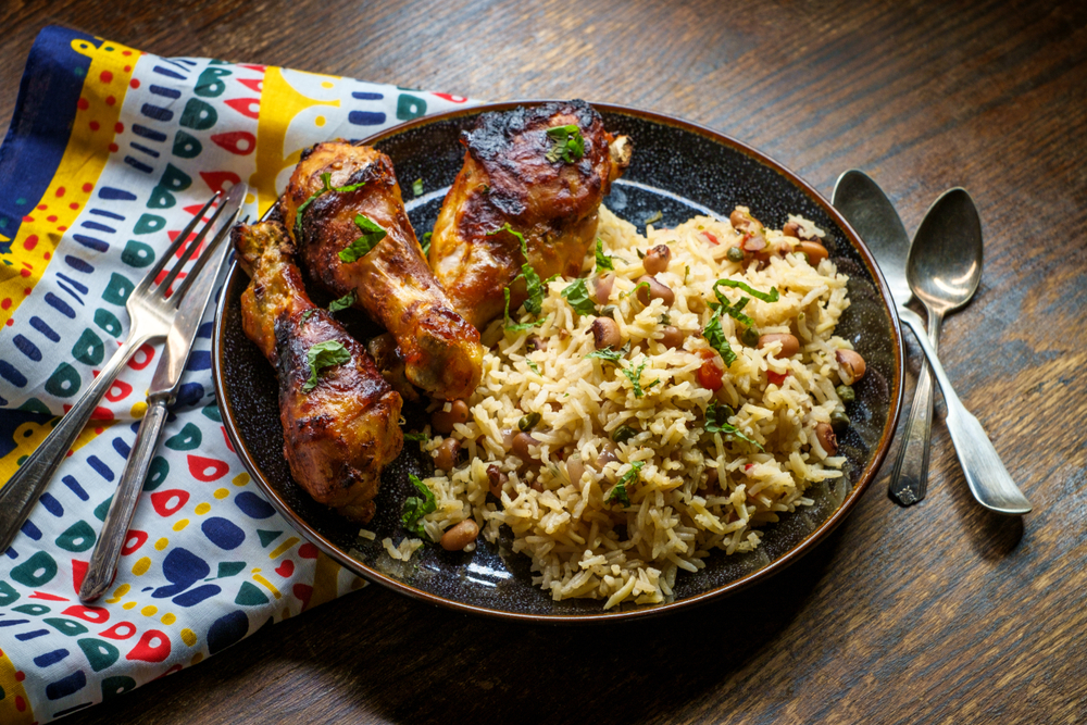 A plate of chicken legs and rice and beans in a West African cooking style similar to what you'll find at some Black owned restaurants in Washington DC
