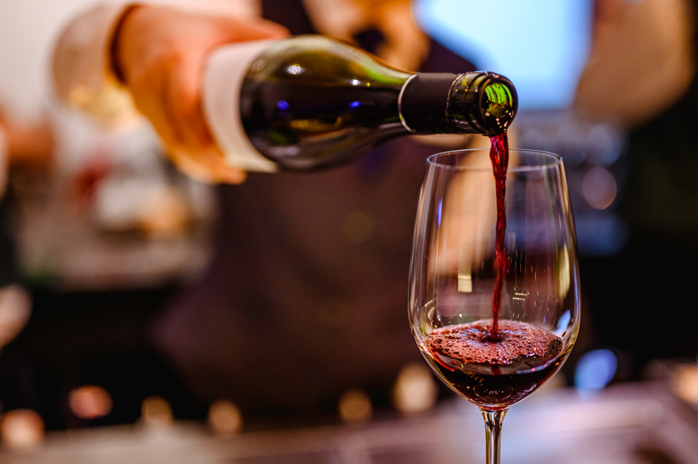 red wine being poured into a wine glass on a bar