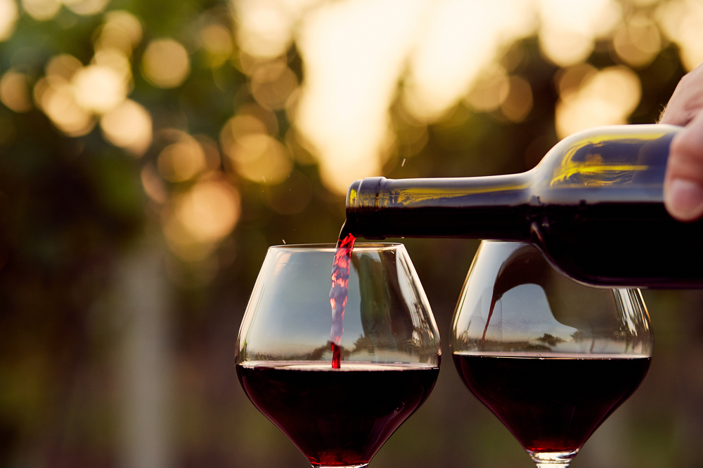 two glasses of wine being poured outside