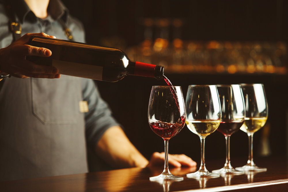 Wine being poured into a glass on a bar.