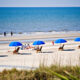 people sitting on a Hilton Head beach with blue umbrellas and white sand