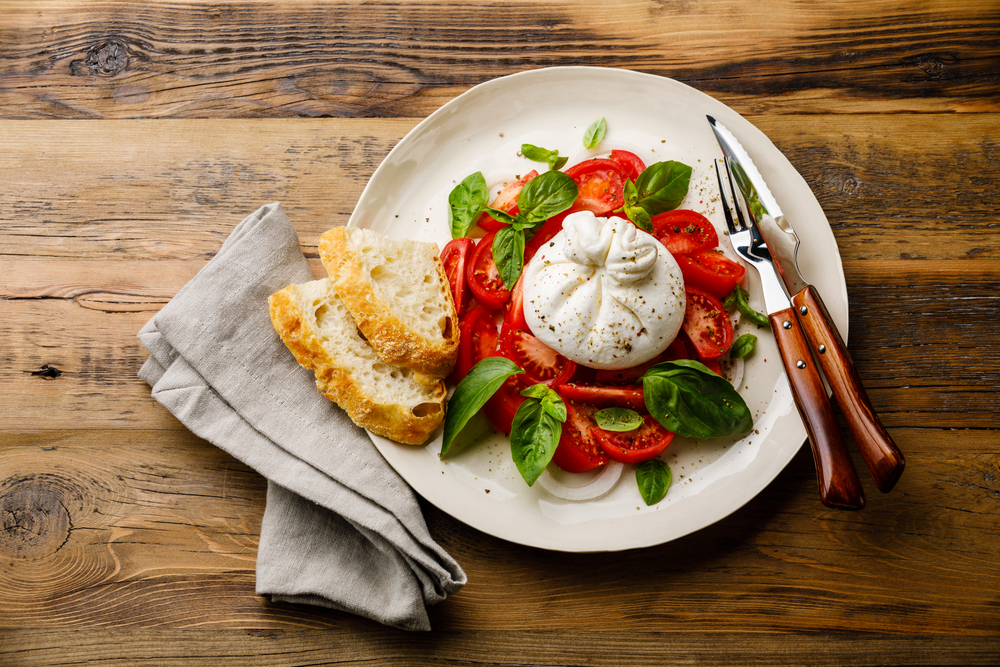 a fresh tomato, basil, and burrata cheese salad paired with some delicious bread, a staple in Italian cuisine!
