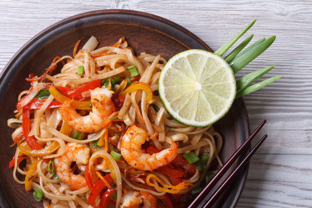 a great bowl of thai noodles, a healthy portion of shrimp and limes!