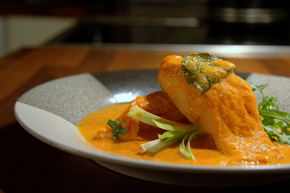 Salmon with red curry paste and coconut milk, decorated with some salad and lime leaves