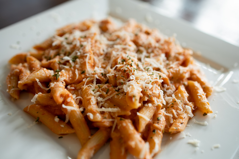 Penne alla Vodka is a classic Italian pasta dish made with penne in a creamy tomato and vodka sauce close-up in a plate on the table with fork
