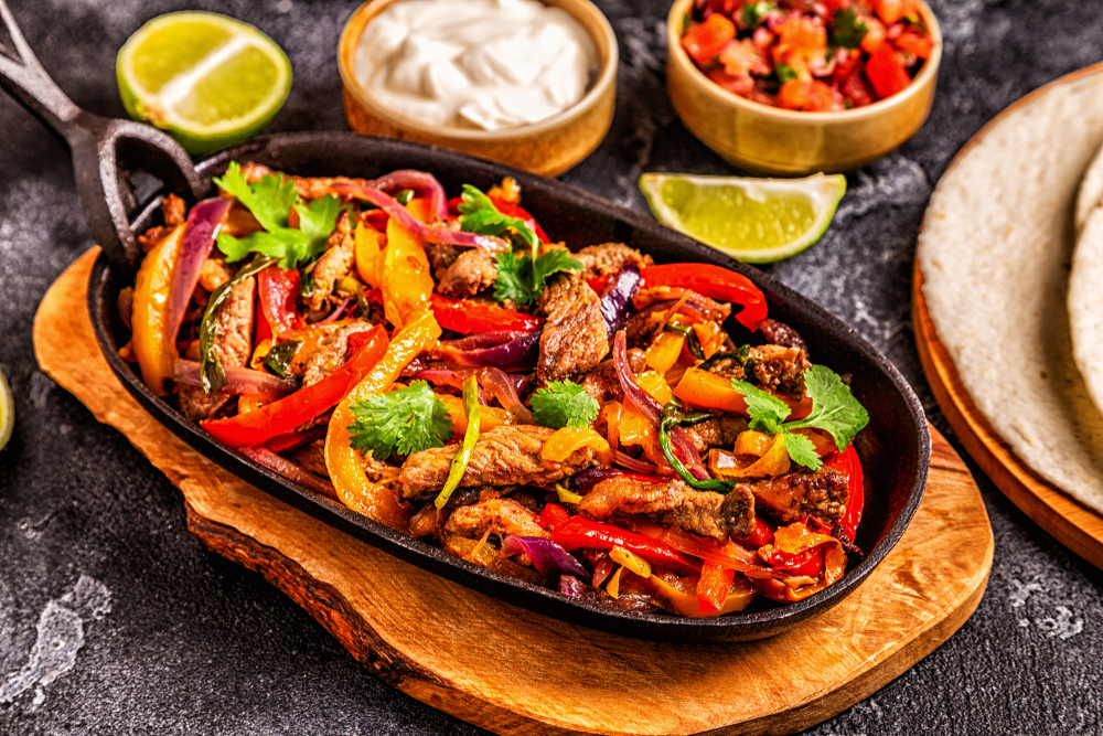 Fajitas with colored pepper and onions, served with tortillas, salsa and sour cream.