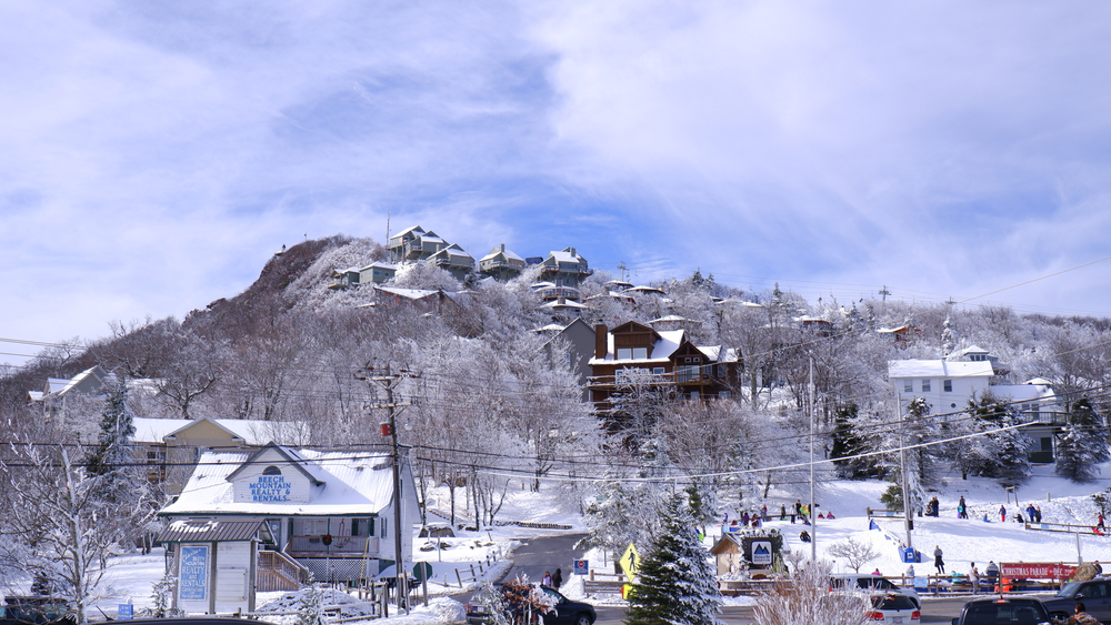a snow covered beech mountain with buildings and people on the mountain