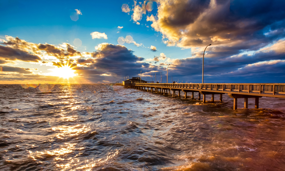 long pier at an Alabama small town over the water at sunset with clouds and waves