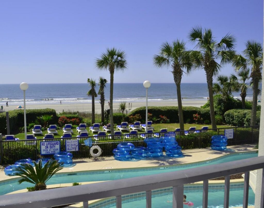 the view from one of the balconies looking over the pool and the Atlantic Ocean with palm trees in Myrtle Beach 