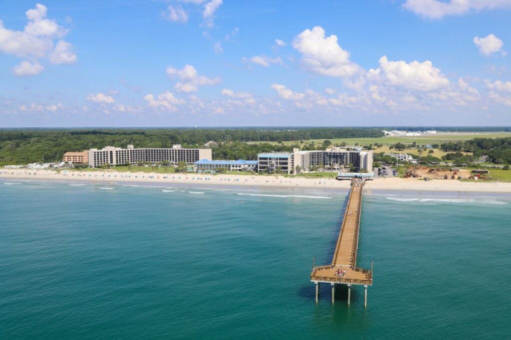 an Ariel view of the oceanfront hotels in Myrtle Beach with a long fishing pier that comes out into the ocean. 