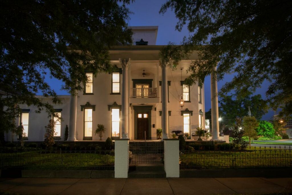 A picture of the exterior of the belle louise historic house at night, the exterior is antebellum style with white columns on the front porch, one of the best resorts in Kentucky 