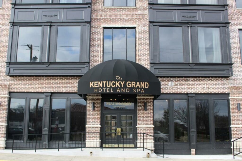 A picture of the front of the Kentucky Grand Hotel and Spa, the building is made of brick and has black trimming and a black awning above the main entrance 