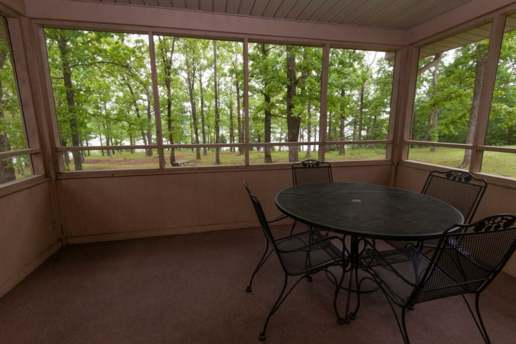 A picture of a semi-covered balcony at the Kenlake State Resort, the view includes the edge of the lake that is obscured by many trees, one of the best resorts in Kentucky 