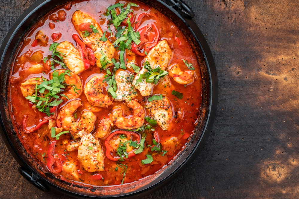 a large pot of gumbo with shrimp and peppers in it, garnish on top