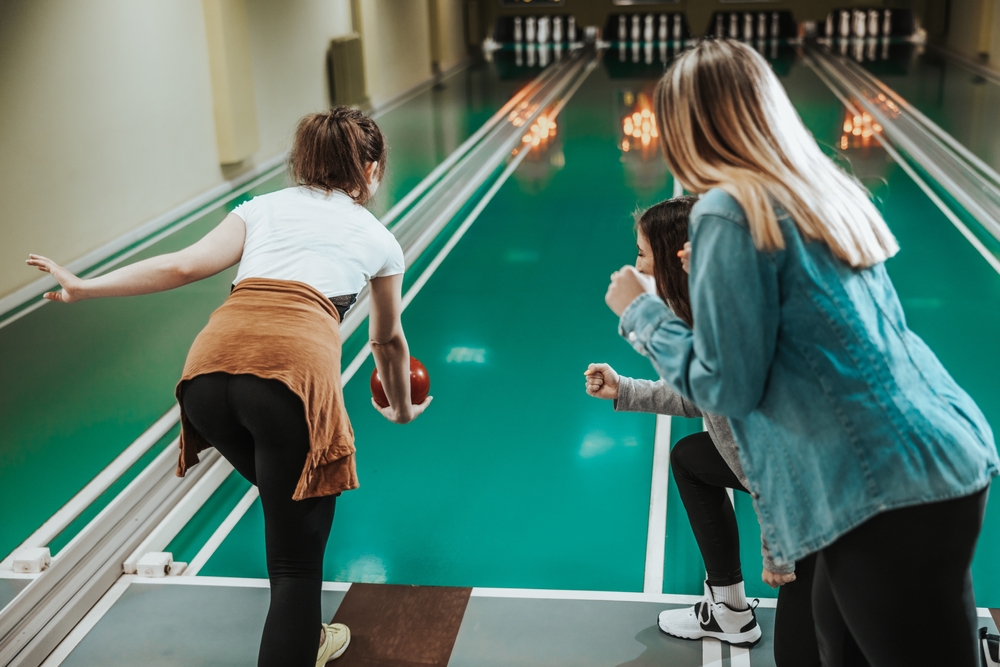 A group of women playing duckpin bowling at a small bowling alley