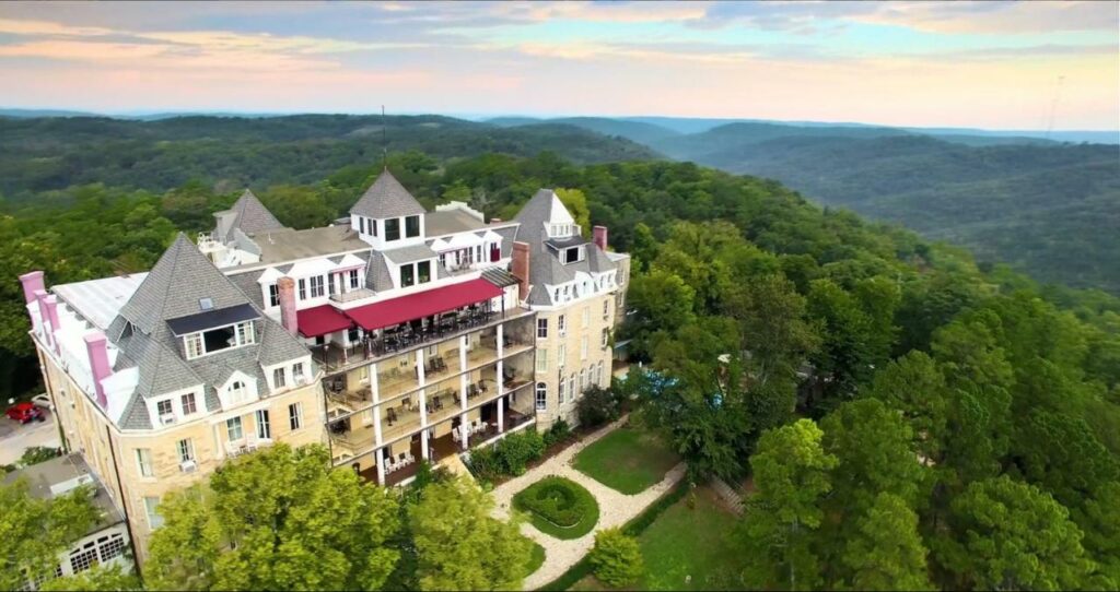 aerial photo of old hotel in the mountains surrounded by trees
