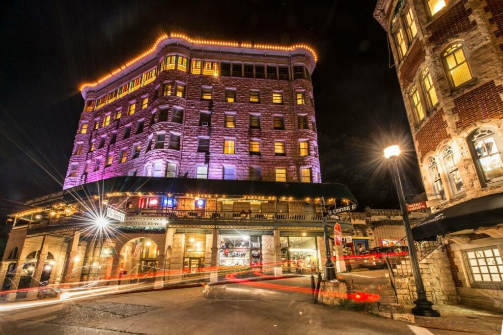 outside photo of hotel lit up with lights at night time, hotel has a balcony restaurant showing in the front 