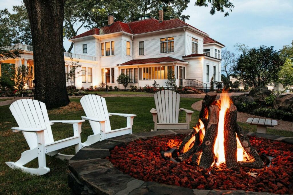 historic inn in background, tree on the left, chairs around a fire in the foreground