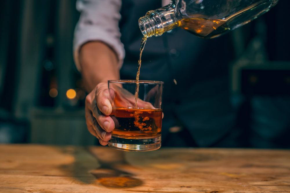 Hand holding a glass while pouring in Tennessee whiskey.